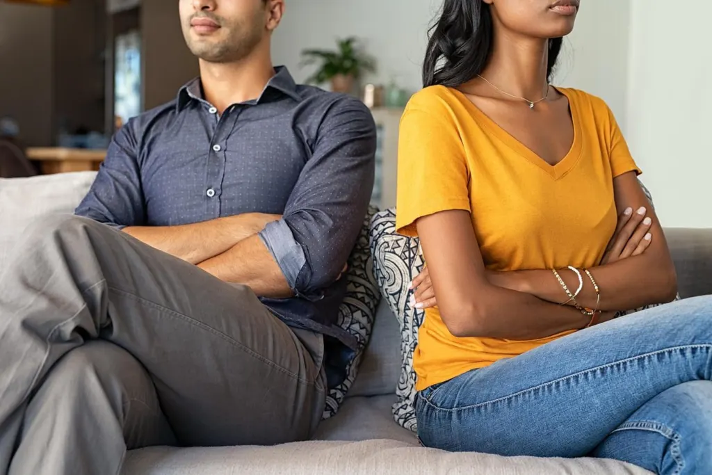 A couple crossing their arms while sitting away from each other on a couch | grief therapist in san francisco, ca | grief therapy in san francisco, ca | grief counseling san francisco, ca | 94110 | 94112 | 94116