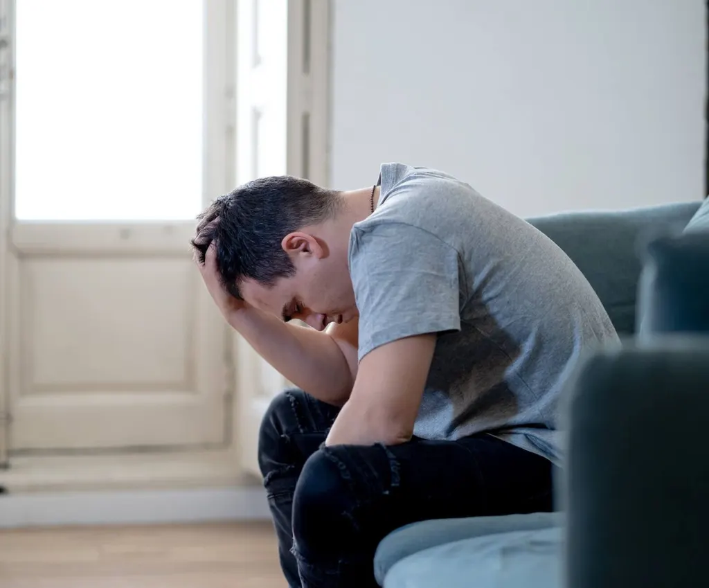 A white man holding the top of his heads in his hand sitting down | grief counseling san francisco, ca | grief therapy san Francisco | grief therapist in san francisco, ca |  94609 | 94061 | 94941