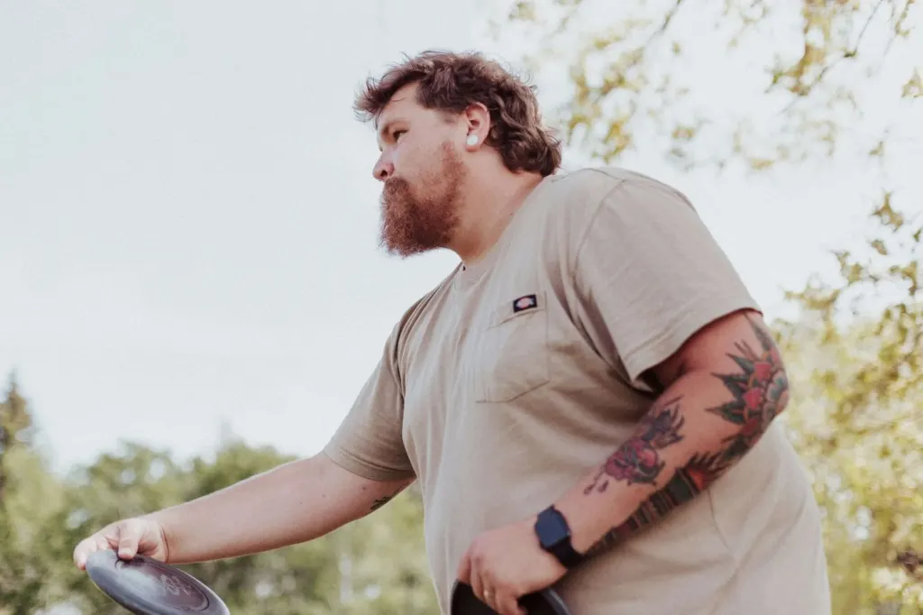 A man with tattoos & a beard throwing a frisbee | men's counseling san francisco, ca | men's therapy san francisco, ca | online men's issues counseling california | 94110 | 94112 | 94116